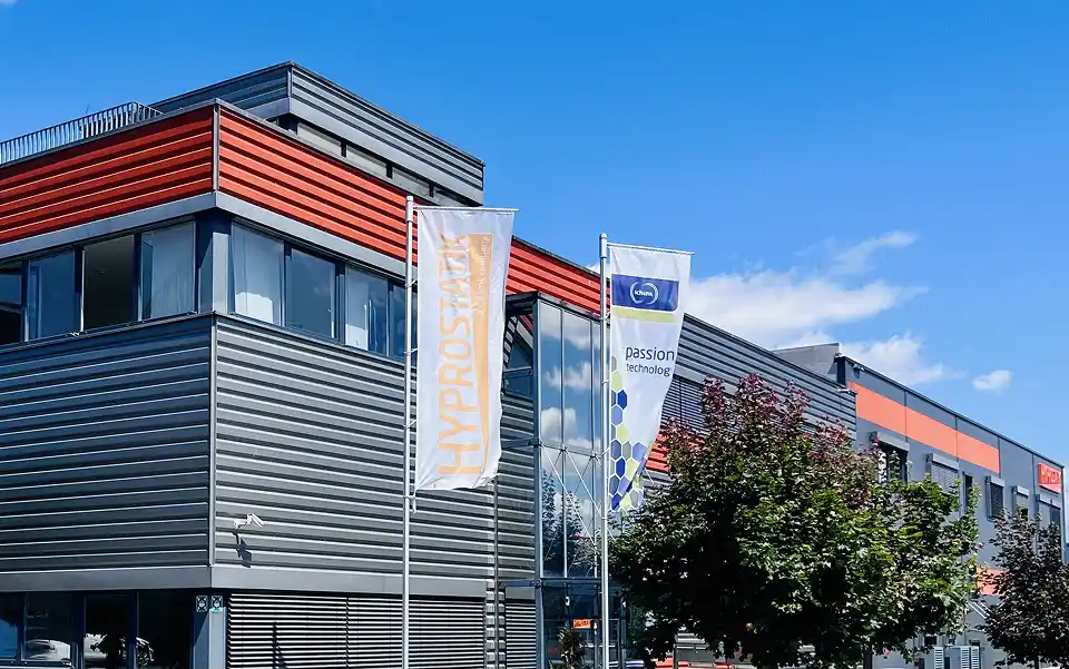 Firmengebäude von HYPROSTATIK mit Flaggen am Standort in moderner Industriearchitektur